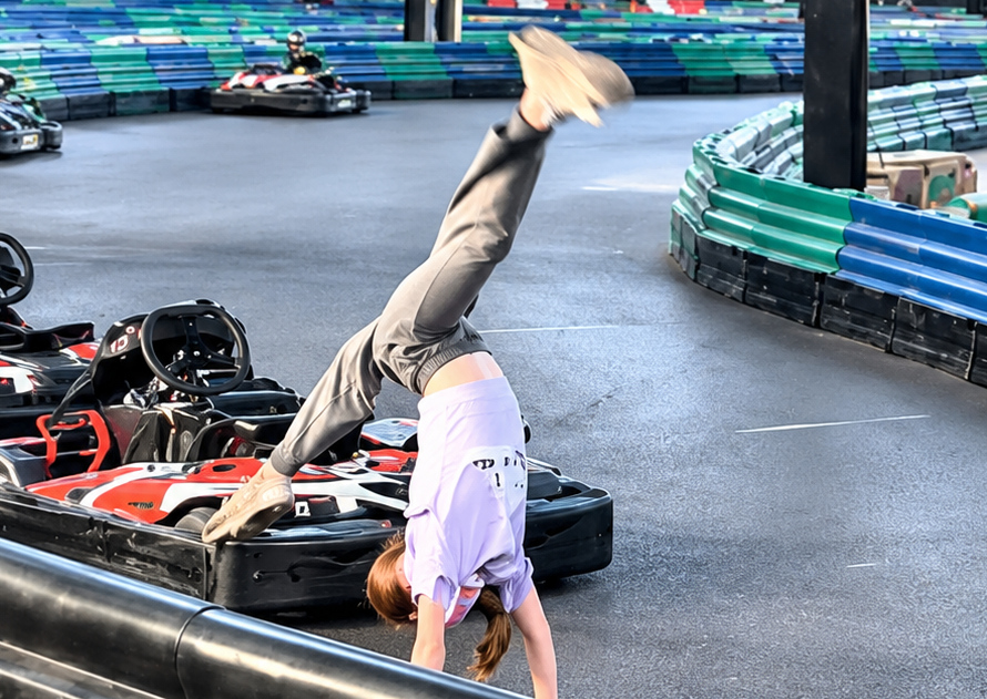 Charlotte zeigt einen Handstand neben den Karts
