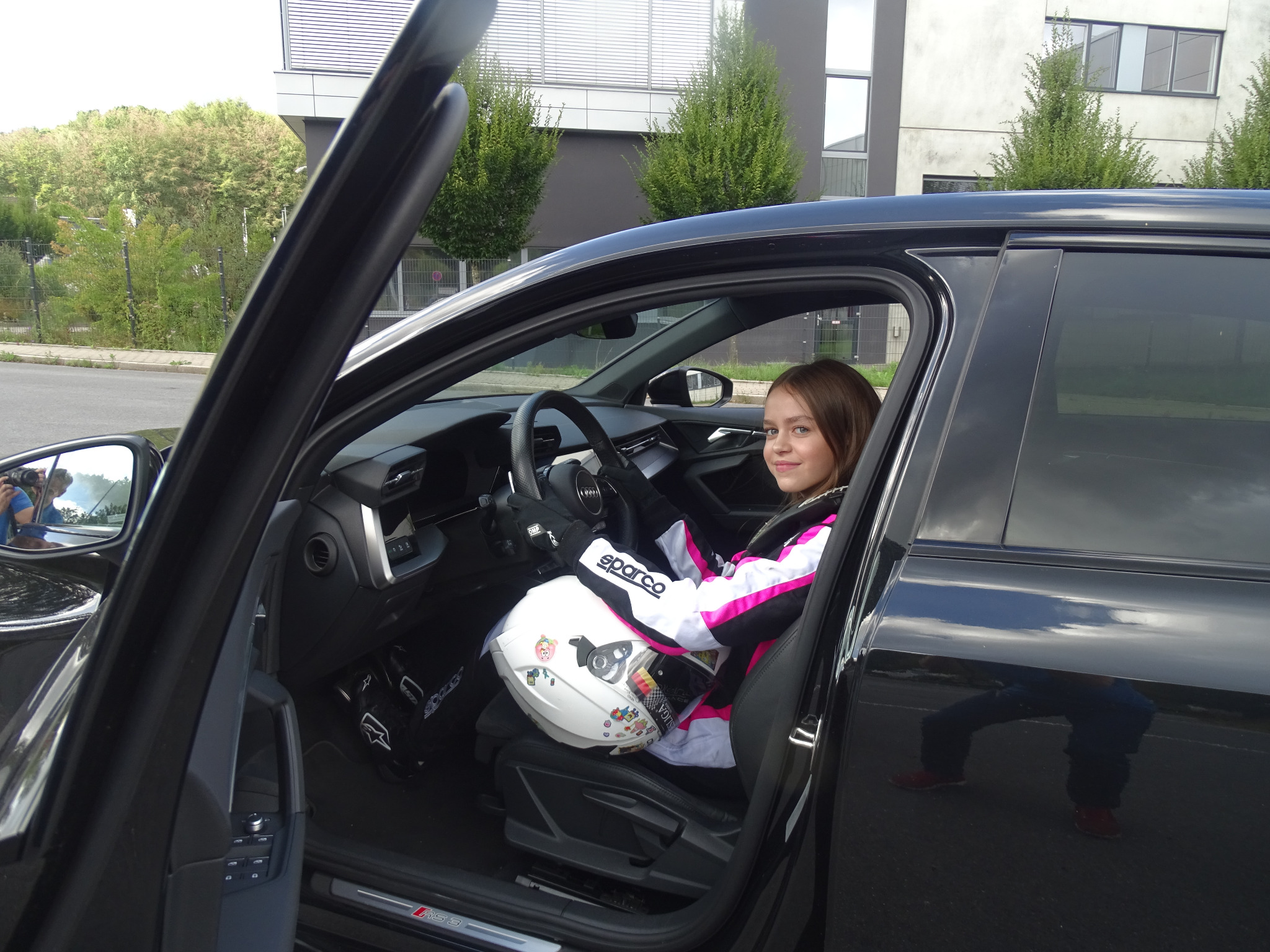 Junge Fahrerin im Rennanzug mit Helm im Fahrzeug
